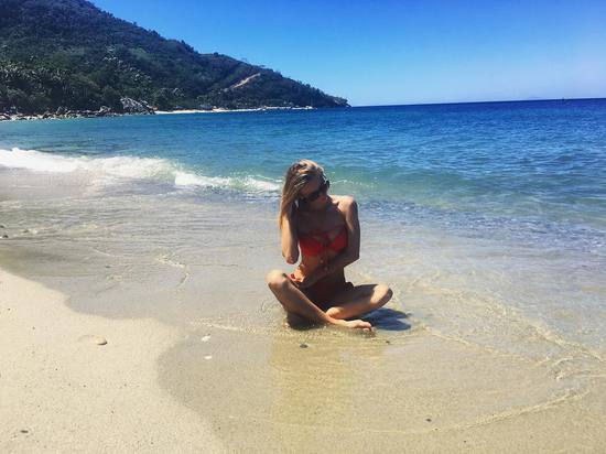 Liliia在赛场边的看台上席地而坐,背景是空旷的球场,她甜美的笑容与静谧的赛场形成独特的美感