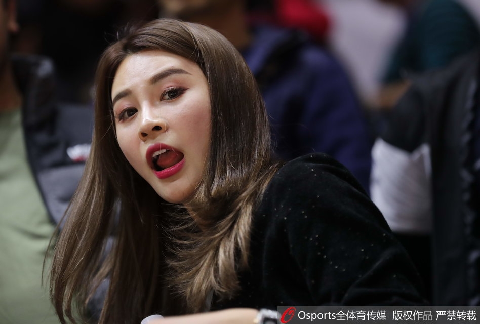 李根爱妻凝望赛场，眼神中满是关切，一头秀发与精致侧颜在看台灯光下显得格外温柔。