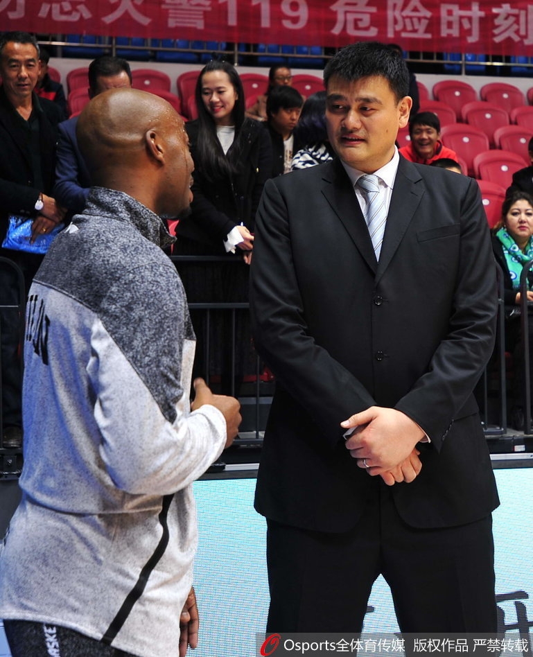 兰德里面带微笑，神情专注地倾听姚明说话，姚明则伸手比划着，两人之间的互动自然又默契，老友相见分外亲切。