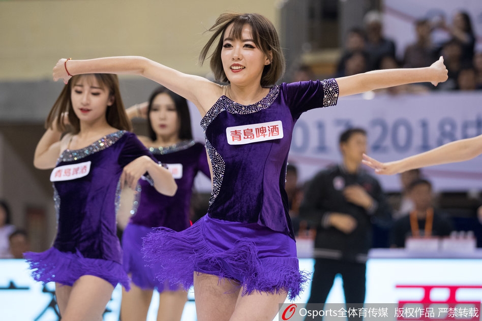 几位篮球宝贝蹲在地上围成一圈,似乎正在进行上场前最后的战术讨论与互相加油鼓劲。她们的妆容精致,眼神中充满了对即将开始的表演的期待与坚定。