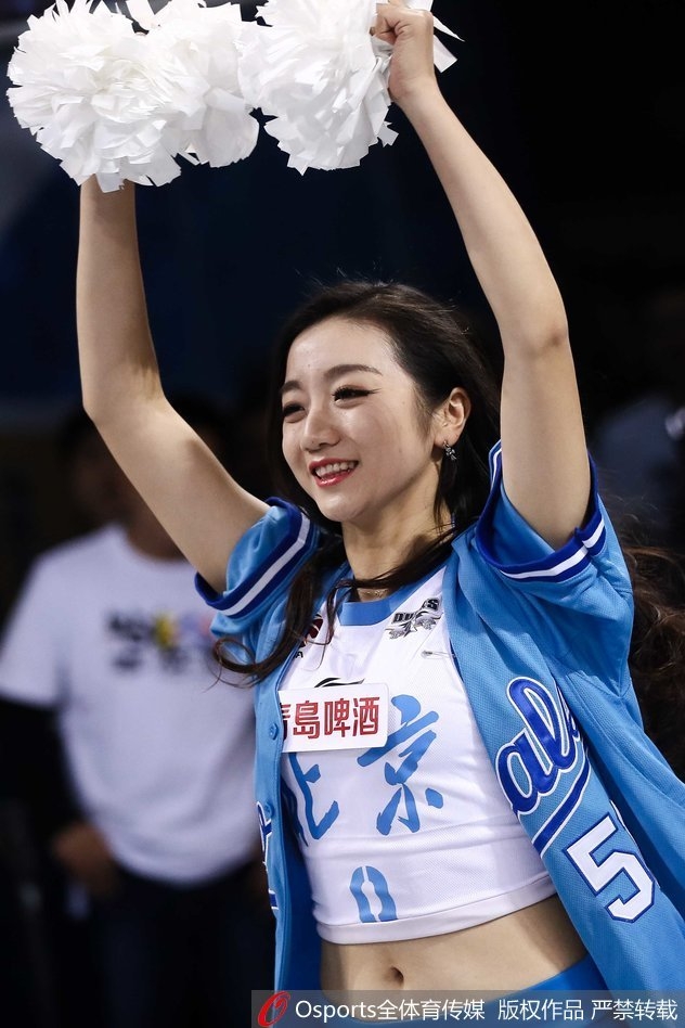 镜头聚焦于一位笑容明媚的宝贝，她挥动着金色的花球，眼神中充满感染力，那份自信与热情足以驱散场馆内所有的紧张空气。