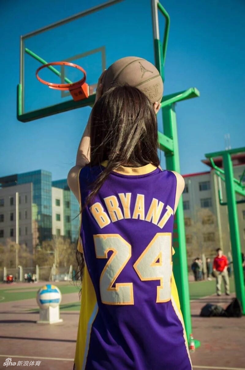 训练间隙，周雪坐在场边休息，修长的双腿自然伸展，她正低头整理护腕，阳光透过球馆窗户洒在她身上，勾勒出柔和的轮廓