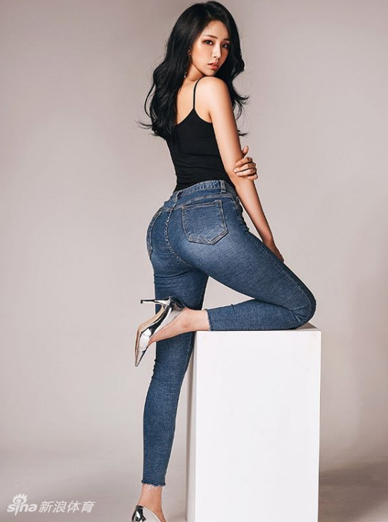 海伦身穿一袭白色连衣裙，站在绿意盎然的背景前，伸手轻触树叶，画面纯净美好，宛如夏日里的一缕清风。