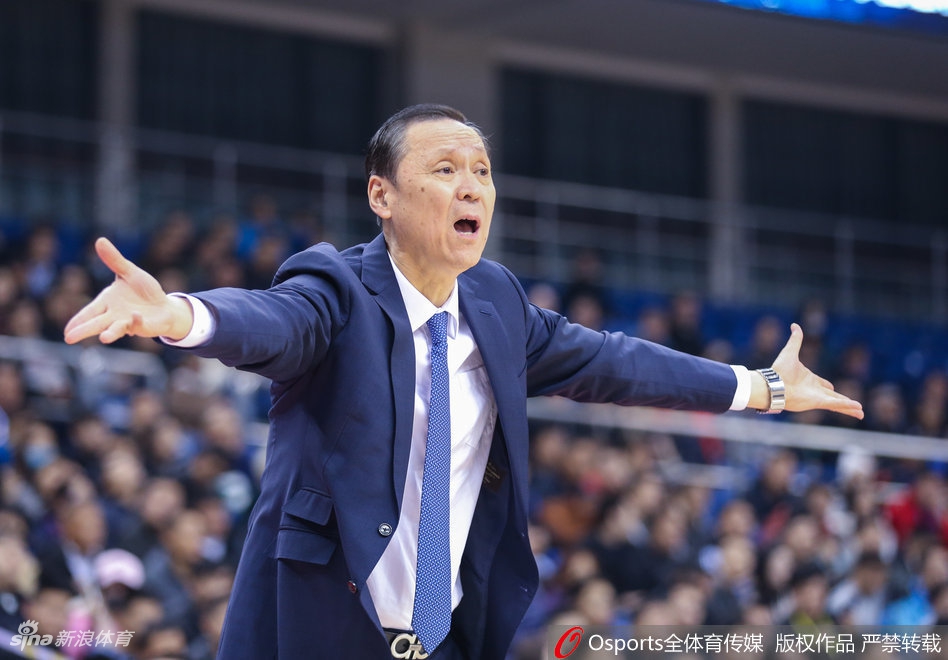 青岛队球员王庆明在命中投篮后握拳怒吼庆祝，身后的球迷看台一片欢腾，挥舞着手中的加油棒