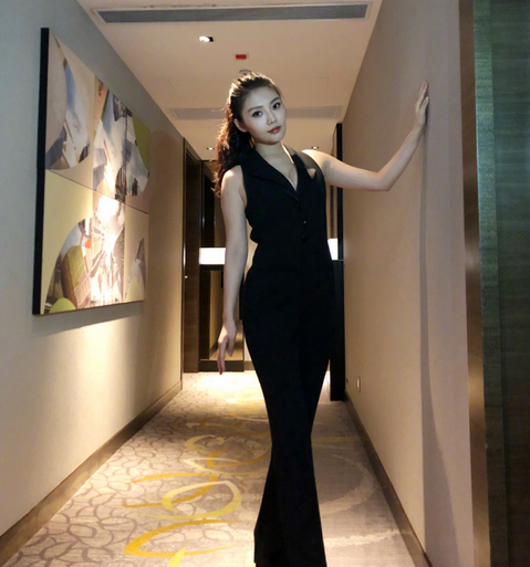 在一组创意写真中，徐冬冬模仿橱窗模特的姿态静静站立，她身穿淡粉色修身针织衫与棕色长裤，显得温婉干练。紧身衣物完美贴合她的身体曲线，展现出健康而饱满的体态，与身旁略显单薄的假模特构成一幅有趣又充满视觉冲击力的画面。