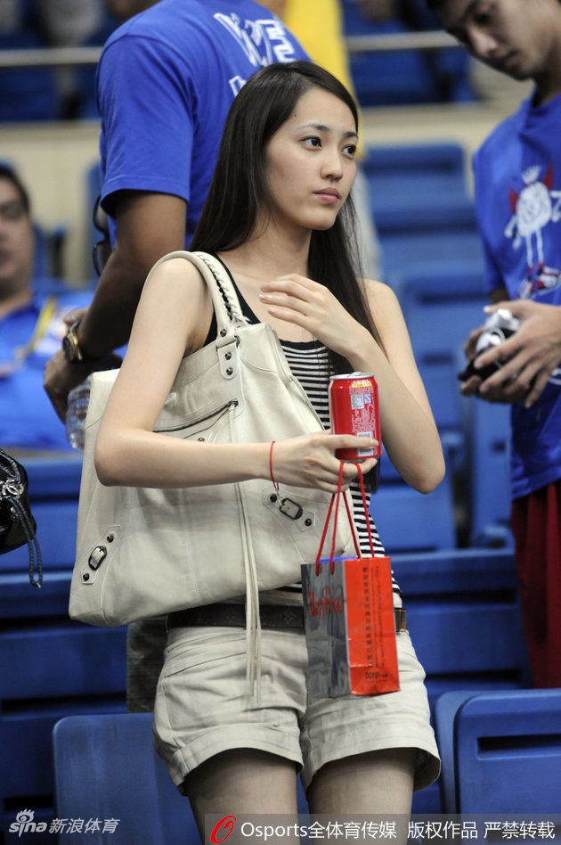 王棠云身穿深色外套站在球场通道内，双手插兜回眸面对镜头，身后是空荡的坐席与明亮的灯光