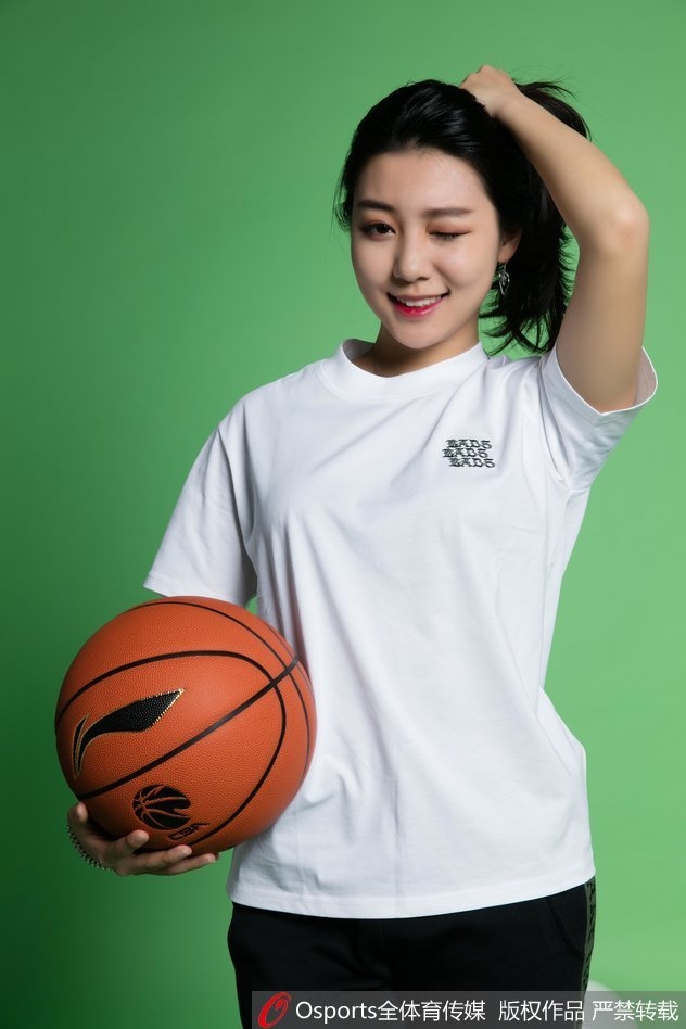 双手轻轻比出爱心手势置于眼前，女孩闭上一只眼俏皮瞄准，仿佛在用这个甜蜜的姿势向镜头那端的球迷发射一颗无形的“爱心子弹”，古灵精怪的模样令人忍俊不禁。