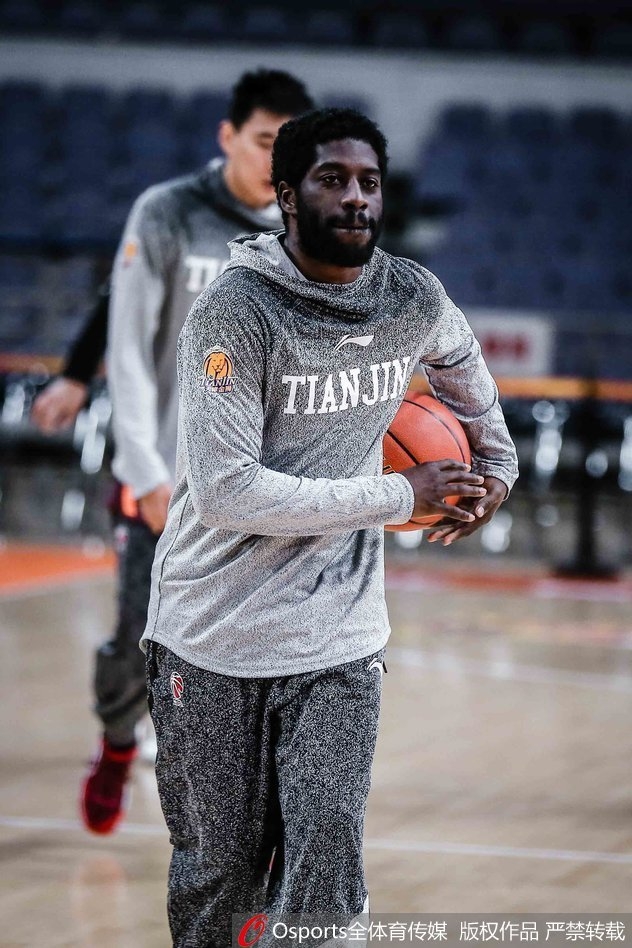 主教练手持战术板，神情严肃地为队员们讲解跑位路线，队员们认真倾听，眼神中充满对胜利的渴望。