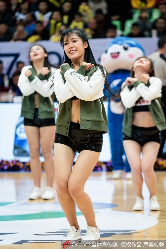 纵排构图下,一名篮球宝贝背对镜头,但依然能感受到她随着节奏扭动的身姿,华丽的服饰下摆飞扬,场边的广告牌和观众席虚化成背景。