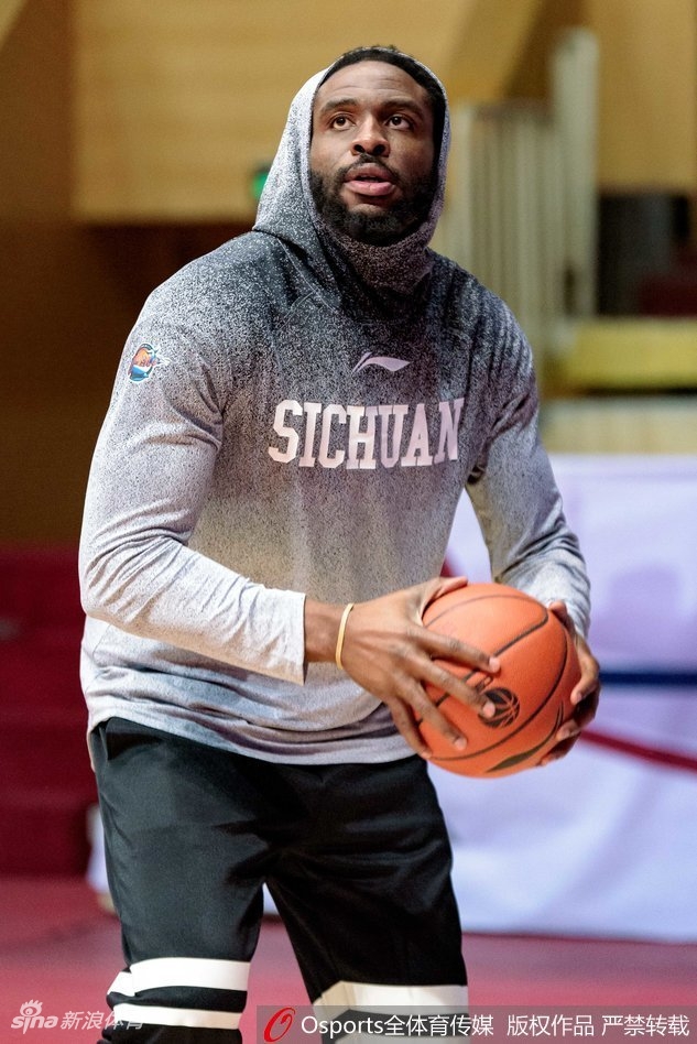 哈达迪在进行拉伸训练,表情略显疲惫但眼神坚毅,手中的热饮在寒冷的球馆里升起袅袅白气。