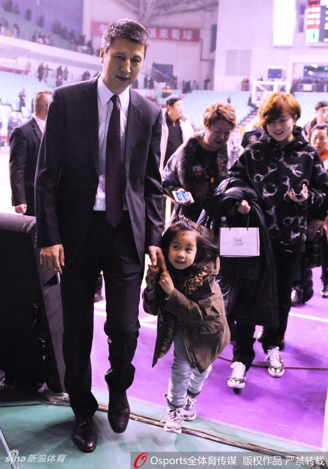 郭士强单手稳稳抱着女儿，小姑娘穿着厚厚的冬装，肉嘟嘟的小脸躲在父亲的肩膀后，只露出一只圆溜溜的大眼睛，仿佛在玩捉迷藏，模样十分惹人怜爱