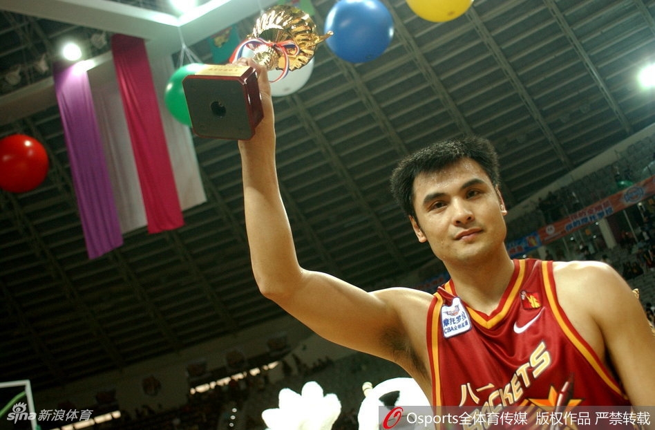 中国篮坛传奇中锋王治郅,身披战袍在对手严密防守下勾手投篮,眼神坚毅,尽显篮下霸主风范。