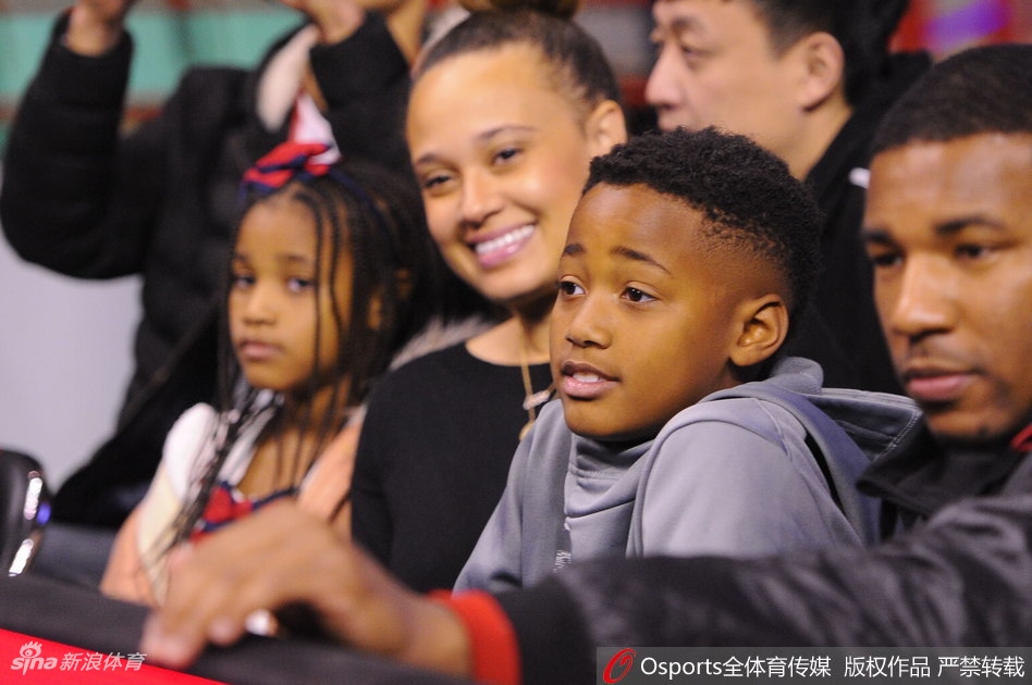 妻子依偎在巴斯身旁，两人目光交汇中满是爱意，周围球迷的喧嚣仿佛都成了他们幸福画面的背景音。