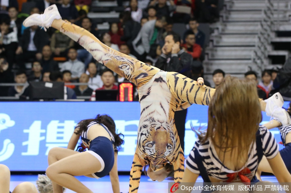 东莞篮球中心光影交错，宏远宝贝身着橙黑相间的虎纹战袍，随着动感鼓点腾空跃起，发丝飞扬间尽显青春野性之美