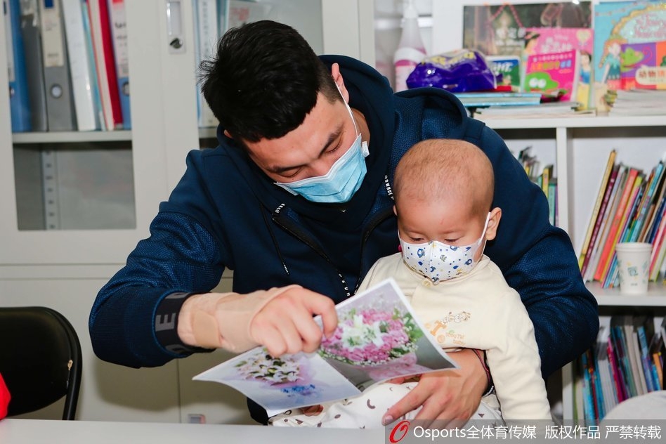 张松涛弯腰将一个大号的霹雳鸭玩偶递给坐在病床上的小朋友,小朋友双手伸出准备接过礼物,眼睛里闪烁着惊喜与兴奋的光芒,旁边病床上的家长也露出了欣慰的笑容