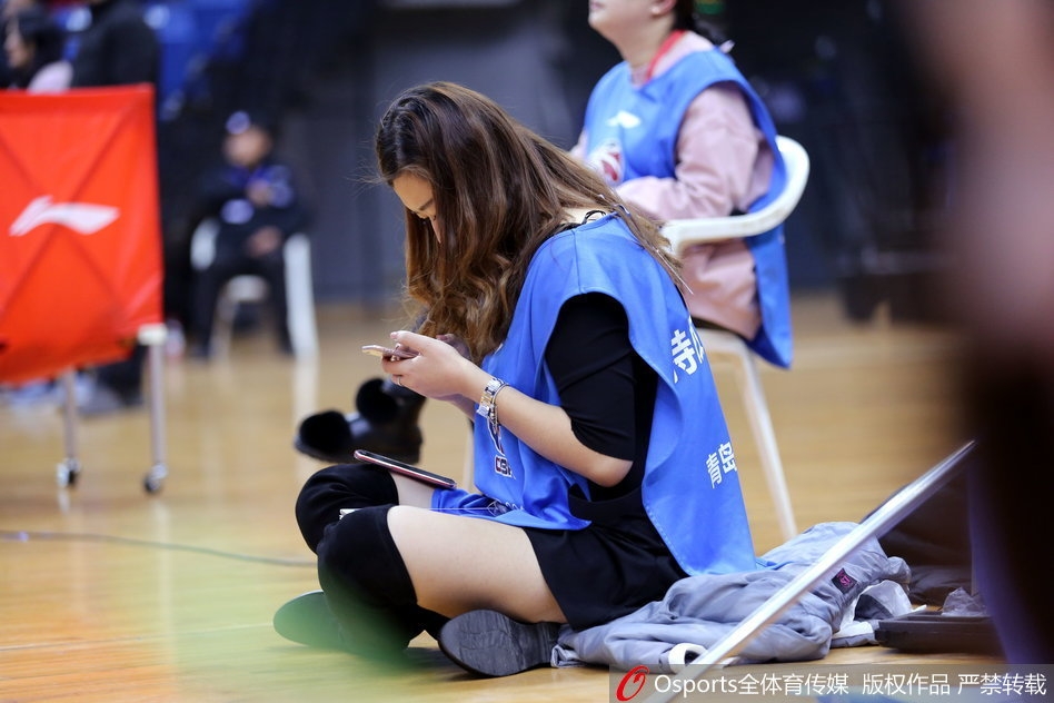 青岛啦啦队宝贝们正在表演一支充满活力的舞蹈，她们动作整齐划一，脸上洋溢着灿烂的笑容，红色短裙随着舞步飞扬，为看台上的球迷们带来了赏心悦目的中场表演。