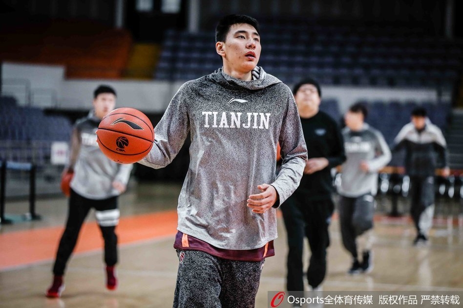 队员们在地板上认真进行拉伸训练，肌肉线条分明，体能教练在一旁细心指导，确保每个动作都发挥最大效果。