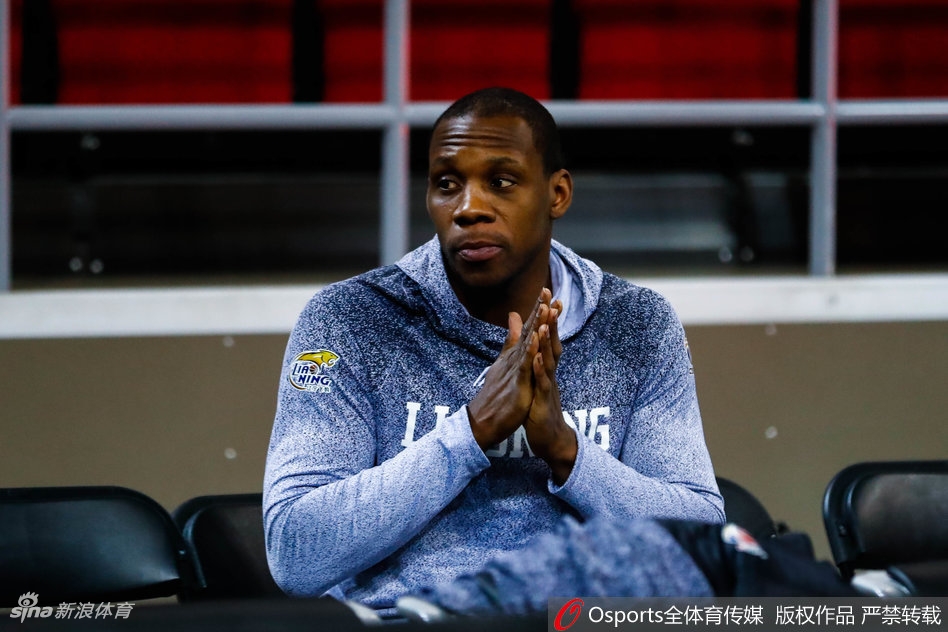 训练场边的矿泉水瓶和毛巾整齐摆放，韩德君在稍作休息，目光望向远方，仿佛在思考着即将到来的比赛策略。