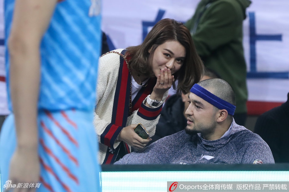 新疆队替补席后的看台上,李根妻子面带微笑为球队的精彩进球鼓掌,身边是热情的北京球迷,她显得优雅又得体。