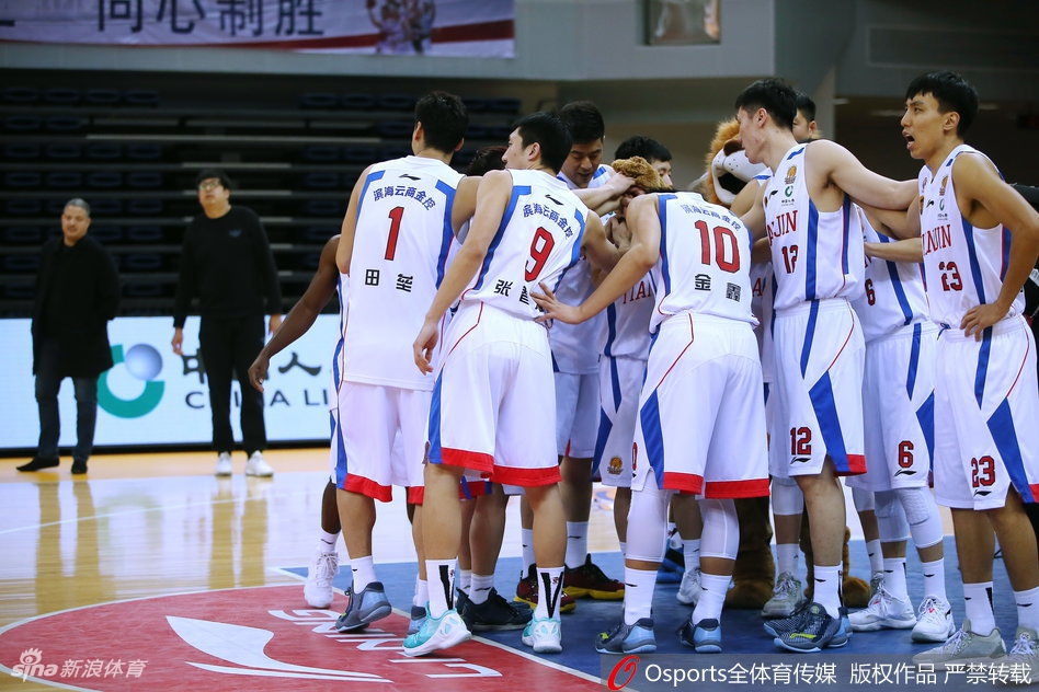 广厦队胡金秋在天津队内线长人阵中高高跃起,以一记轻盈的挑篮躲避封盖,眼神专注而坚定。