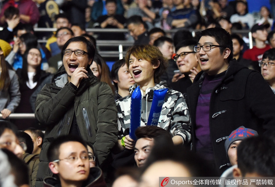 看台上，两位男性球迷激动地起身站立，他们手中展开的纸上用加粗的记号笔写着'小丁，上海小囡欢迎侬'，将上海话与亲切的称呼结合，透露出即便作为对手，上海球迷也对这位山东球星有着天然的亲近感。