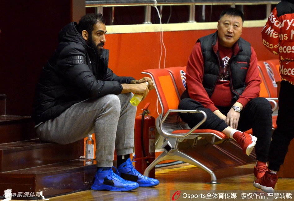 在四川金强队的训练馆内，核心球员哈达迪并未参与合练，他身着便装独自坐在场边的椅子上，双手放在膝盖上，目光凝重地注视着场上队友的每一个跑动和投篮。