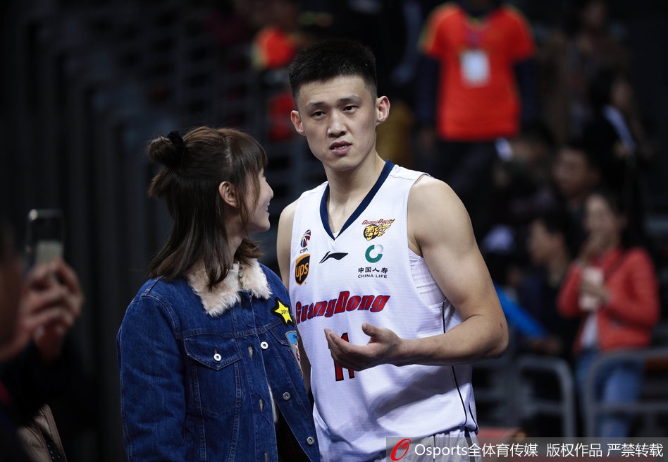 赛场边，周鹏的妻子安静地坐着，简约的穿着难掩出众气质，一双修长美腿在球场灯光下显得格外吸睛。