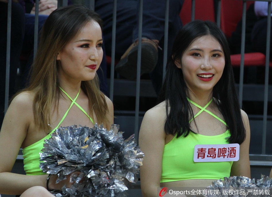 在赛场璀璨的灯光下，两位篮球宝贝背靠背摆出动感造型，修长的身姿与篮球场地板上的倒影相映成趣