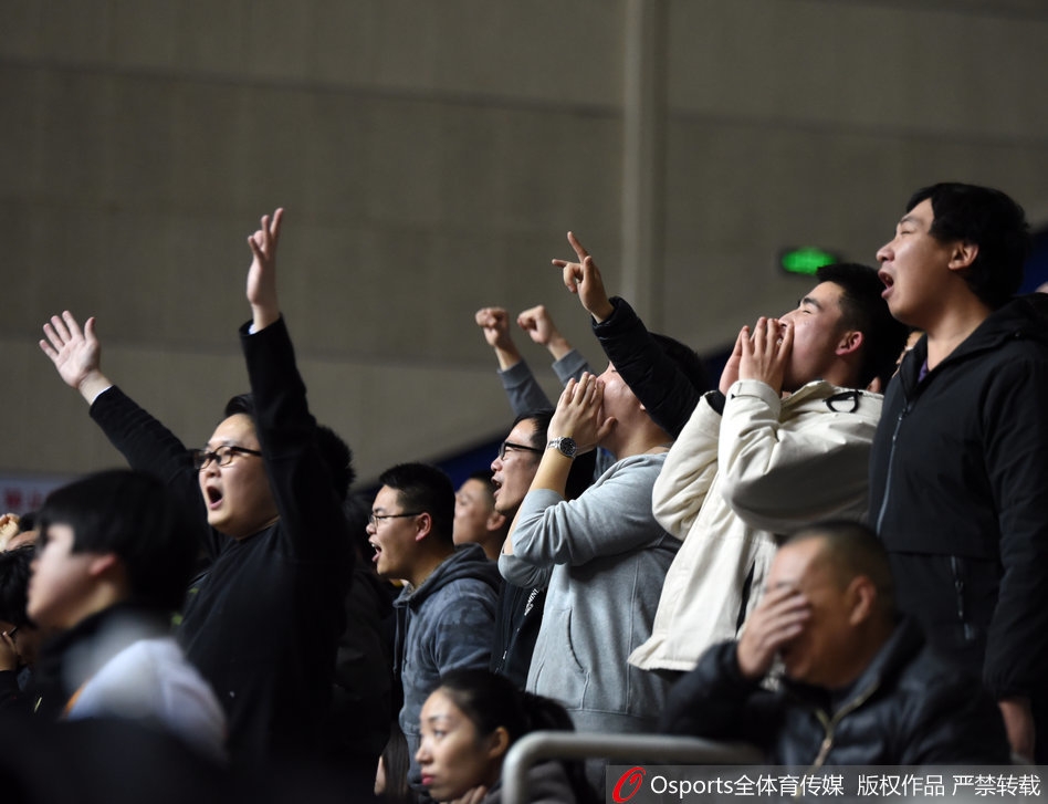 镜头拉近，一位年轻的女球迷脸上贴着上海队的贴纸，双手却高高举着一块平板电脑，屏幕上闪烁着'丁彦雨航，加油！'几个大字，她的眼神中满是对这位国内顶尖球员的欣赏，竞技体育的魅力在这一刻超越了主客场的界限。
