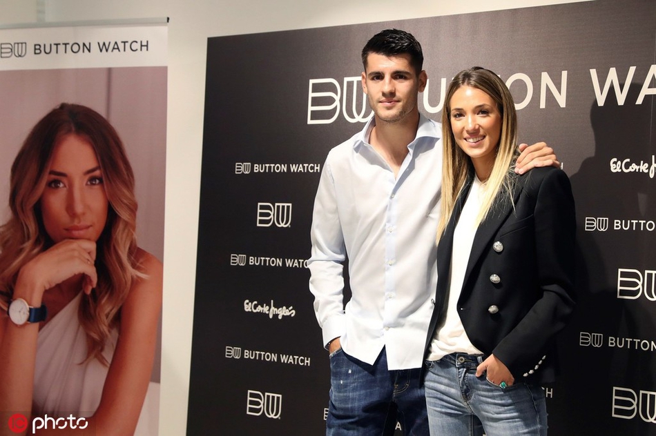 一袭黑色长裙的爱丽丝在背景板前留下倩影，莫拉塔则在不远处微笑着注视，这张抓拍捕捉到了硬汉铁骨下的柔情瞬间