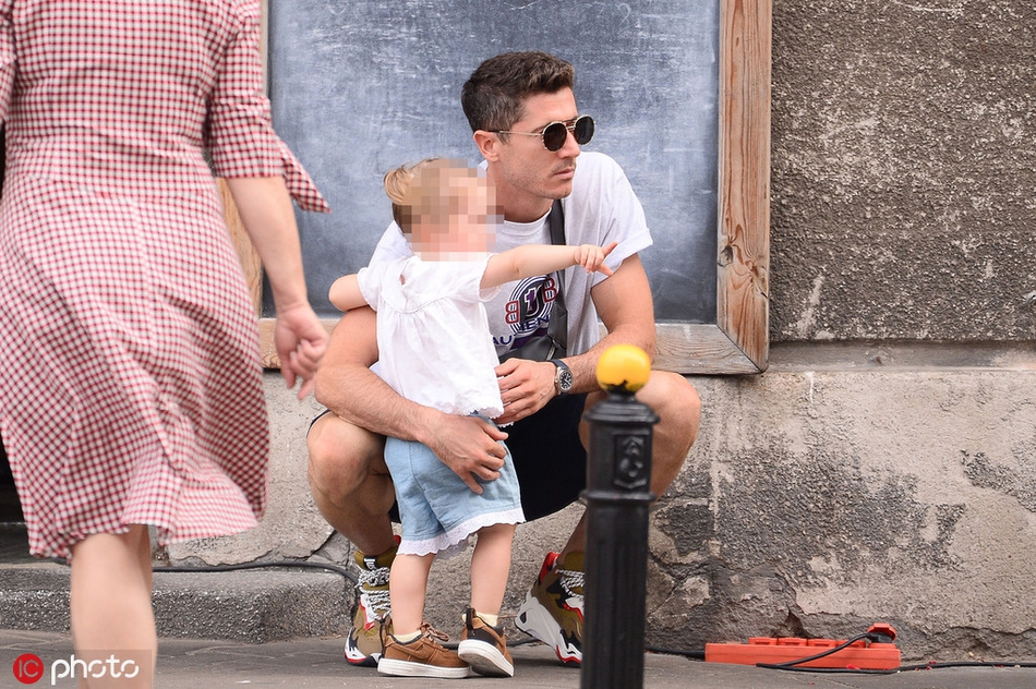 在人来人往的街头，莱万的大女儿骑在父亲的肩头，高高在上地探索着世界，而安娜则在一旁温柔地注视着自己的丈夫和女儿，画面温馨至极。