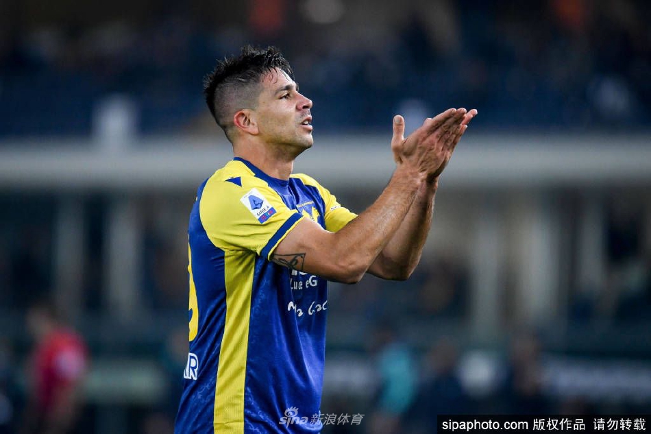 小西蒙尼在签约完成后手持那不勒斯队徽球衣，于俱乐部的荣誉室内向镜头展示，眼神充满坚定与期待。