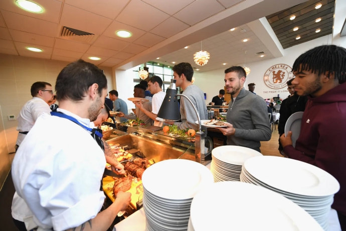 斯坦福桥的餐厅里，璀璨的水晶吊灯下，长桌铺着洁白的桌布，球员们身着休闲正装，正举杯欢庆，笑容比身后的圣诞树更为耀眼。