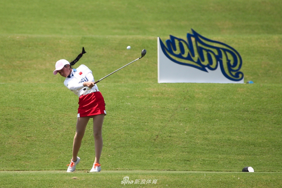 一位女球员正沉稳地进行一号木挥杆，动作流畅充满力量，阳光为她的轮廓镀上金边。