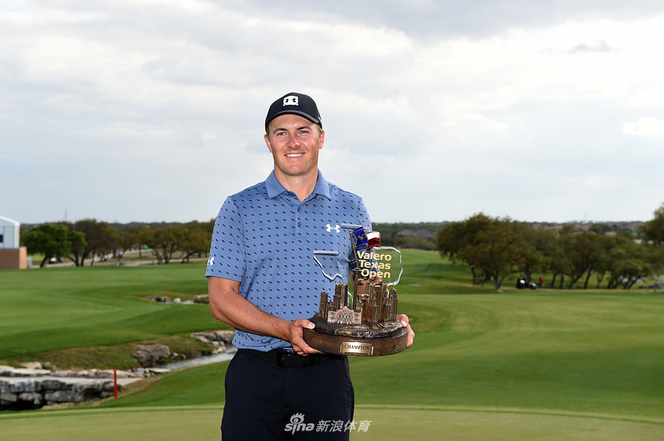 斯皮思在颁奖典礼上高举冠军奖杯，脸上洋溢着如释重负的灿烂笑容，牛仔帽和冠军支票板衬托出浓厚的德州风味。