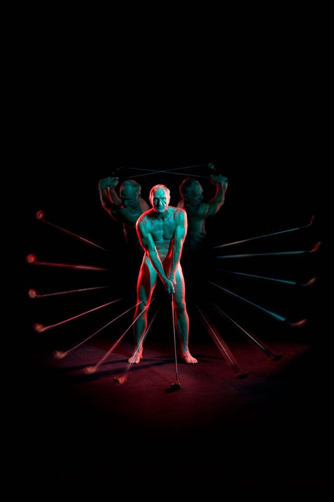 诺曼侧身立于海边，夕阳为其雕塑般的肌肉线条镀上金色轮廓，仿佛一位审视自己领地的海洋王者。