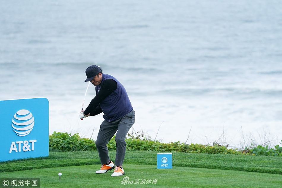 崔虎星在果岭旁与同组球员交流，手持挖起杆，指向果岭起伏的线路，神情认真而投入。