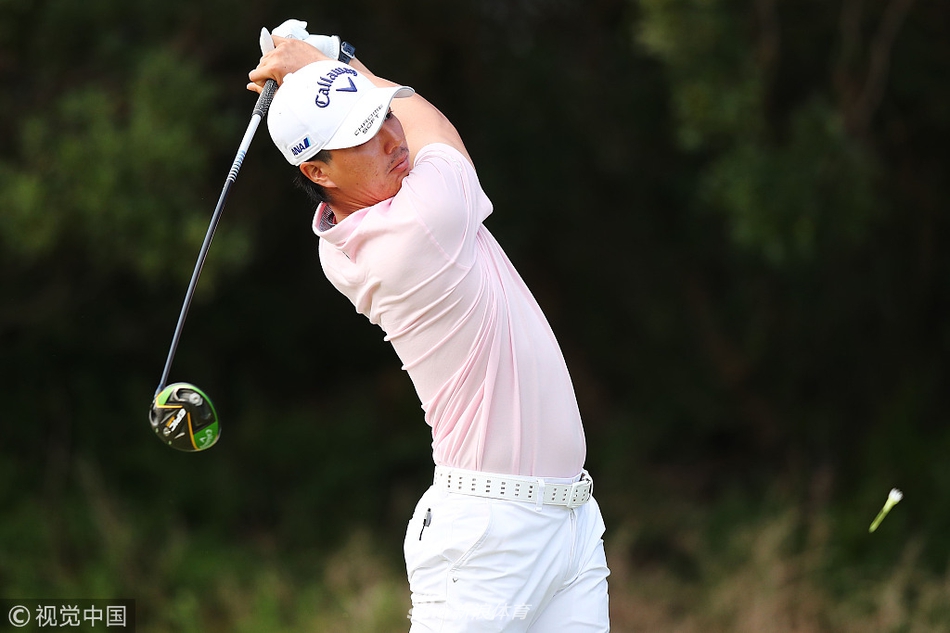 一位球迷悠闲地骑着自行车，停在果岭围绳之外，聚精会神地观看场内球员处理关键推杆。