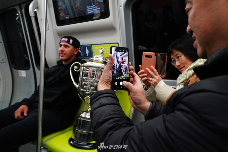 一位幸运的小球迷瞪大眼睛，好奇地伸手轻触奖杯表面，科普卡在一旁露出鼓励的笑容