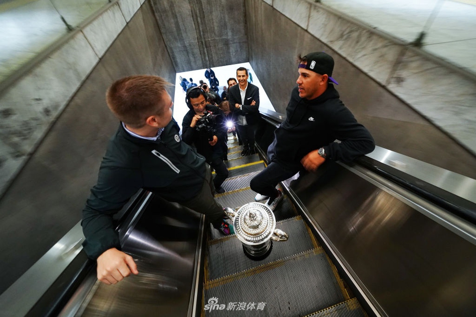 科普卡怀抱奖杯倚靠在车厢连接处，眼神笃定望向窗外飞逝的城市景观，仿佛在思考卫冕之路