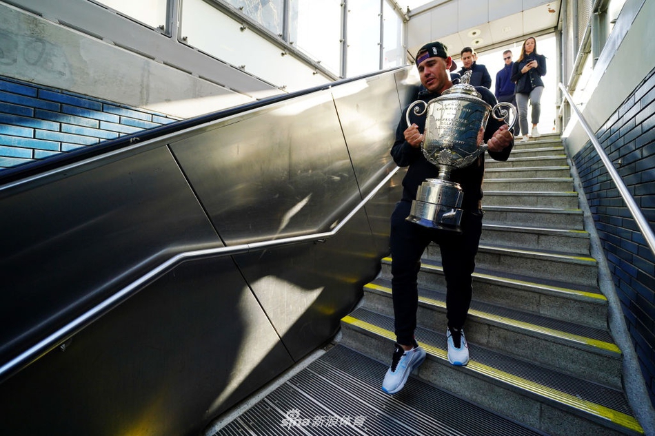 旅程结束，科普卡手提奖杯箱走出地铁站，夕阳为他的背影镀上金光，寓意着荣耀之路通向更广阔的天地