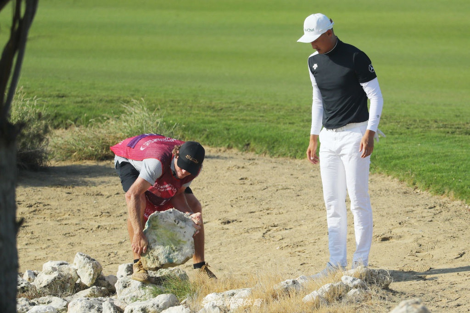 李昊桐挥杆瞬间，球杆在沙坑中扬起一片金色的沙雾，身体在强风中努力保持平衡。
