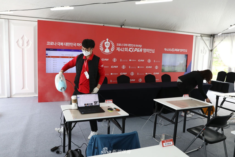 绿意盎然的球场上，一位女球员正俯身进行精准推杆，身旁的球童严格遵守防疫规定佩戴着口罩。