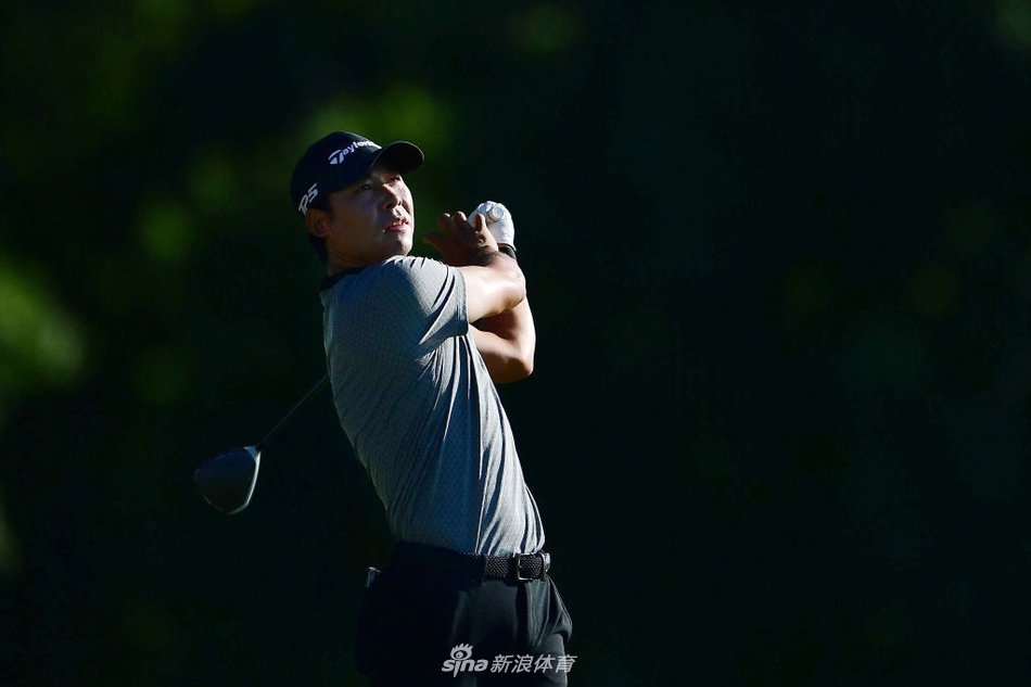 韩国名将崔京周在球道上沉思，经典的短推预备姿势，背景中TPC双子城独具特色的石桥与水域静默相伴