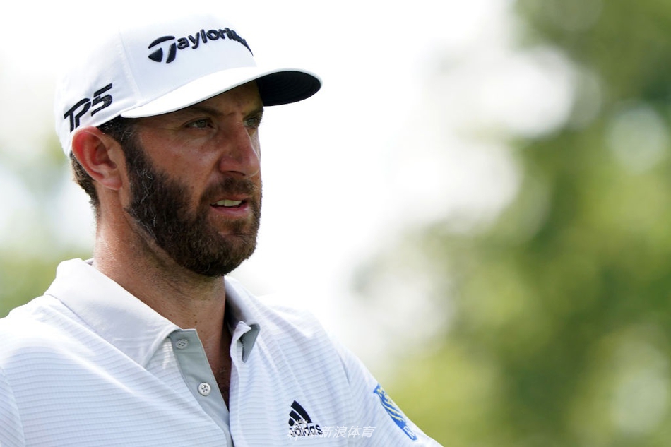 松山英树在奥林匹亚菲尔兹球场果岭边凝神观察，身后是茂密的长草与广阔的天空，展现大赛的凝重氛围