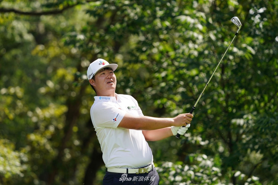 松山英树在巨大记分牌前走过，领先者的名字在阳光下格外醒目