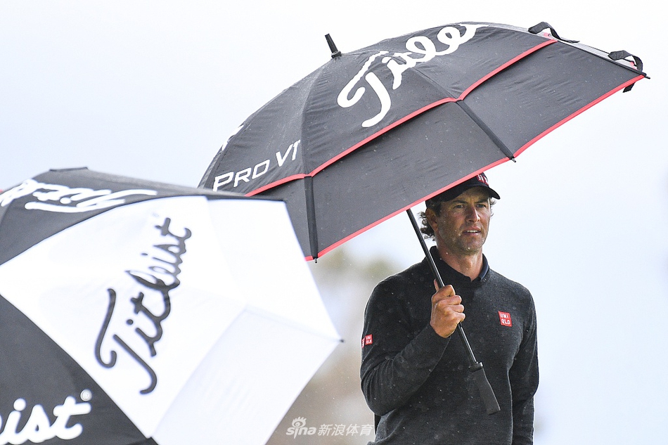 帕特里克·瑞德在强风中稳定站姿准备击球，衣服被风吹动，凸显了天气的挑战。