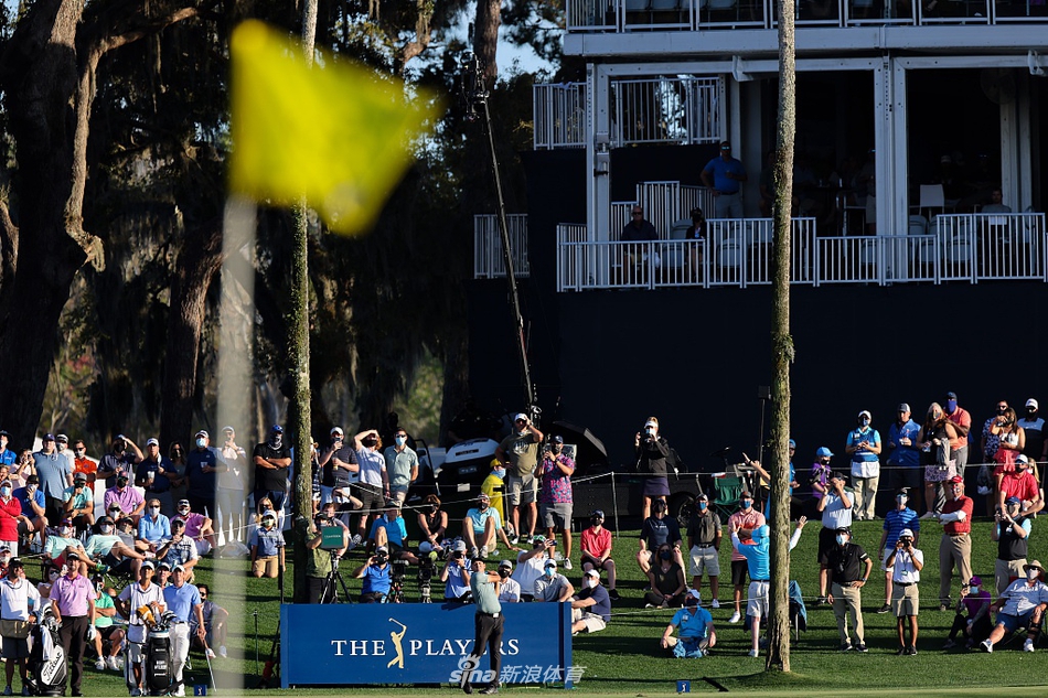 球员锦标赛激烈的次轮竞争中，两位同组球员在球道上并肩行走，一边交流一边走向下一个击球点。