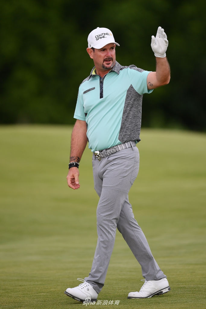 领先者厄维瑞在果岭边审视线路,他身后的记分牌清晰地显示着成绩的变化,悬念已然升起。