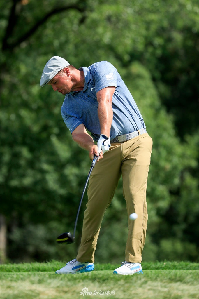 老虎伍兹在果岭上专注推杆，表情凝重，背景中可见经典的球场沙坑与树林